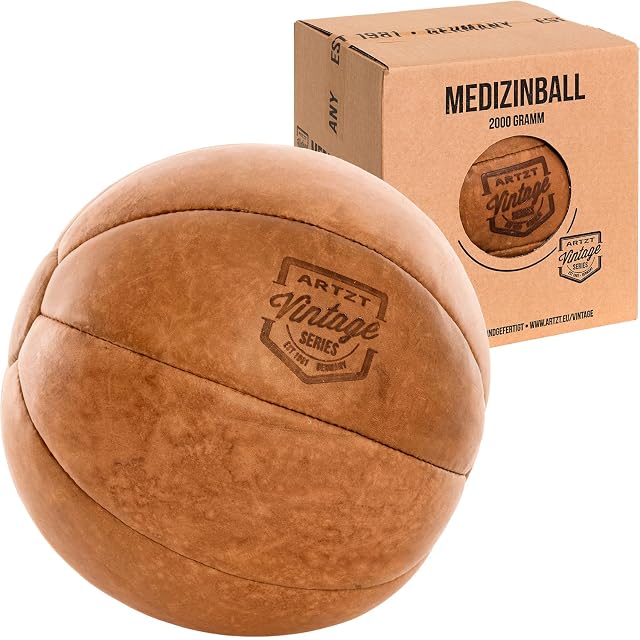 ARTZT Vintage Series Medizinball aus hellbraunem Leder mit eingebranntem Wappen, daneben ein Kraftkarton mit der Aufschrift 2000 GRAMM